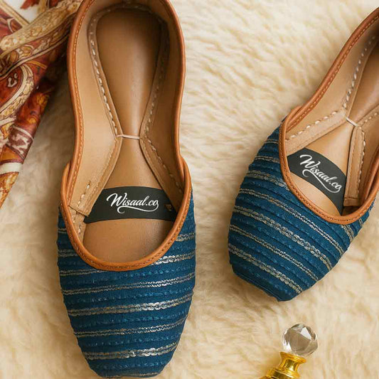 Pair of blue striped shoes with brown soles on a textured surface