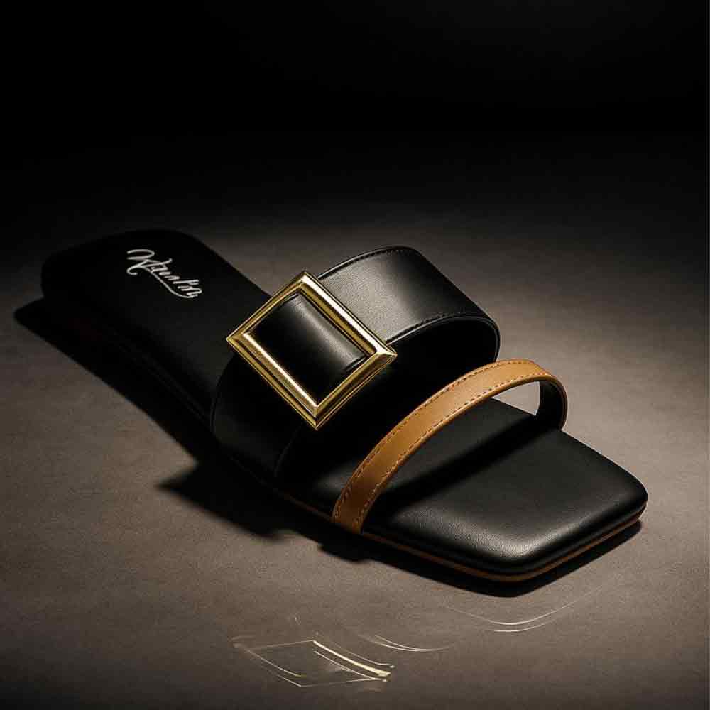 Black slide sandal with gold buckle and brown strap on a dark background